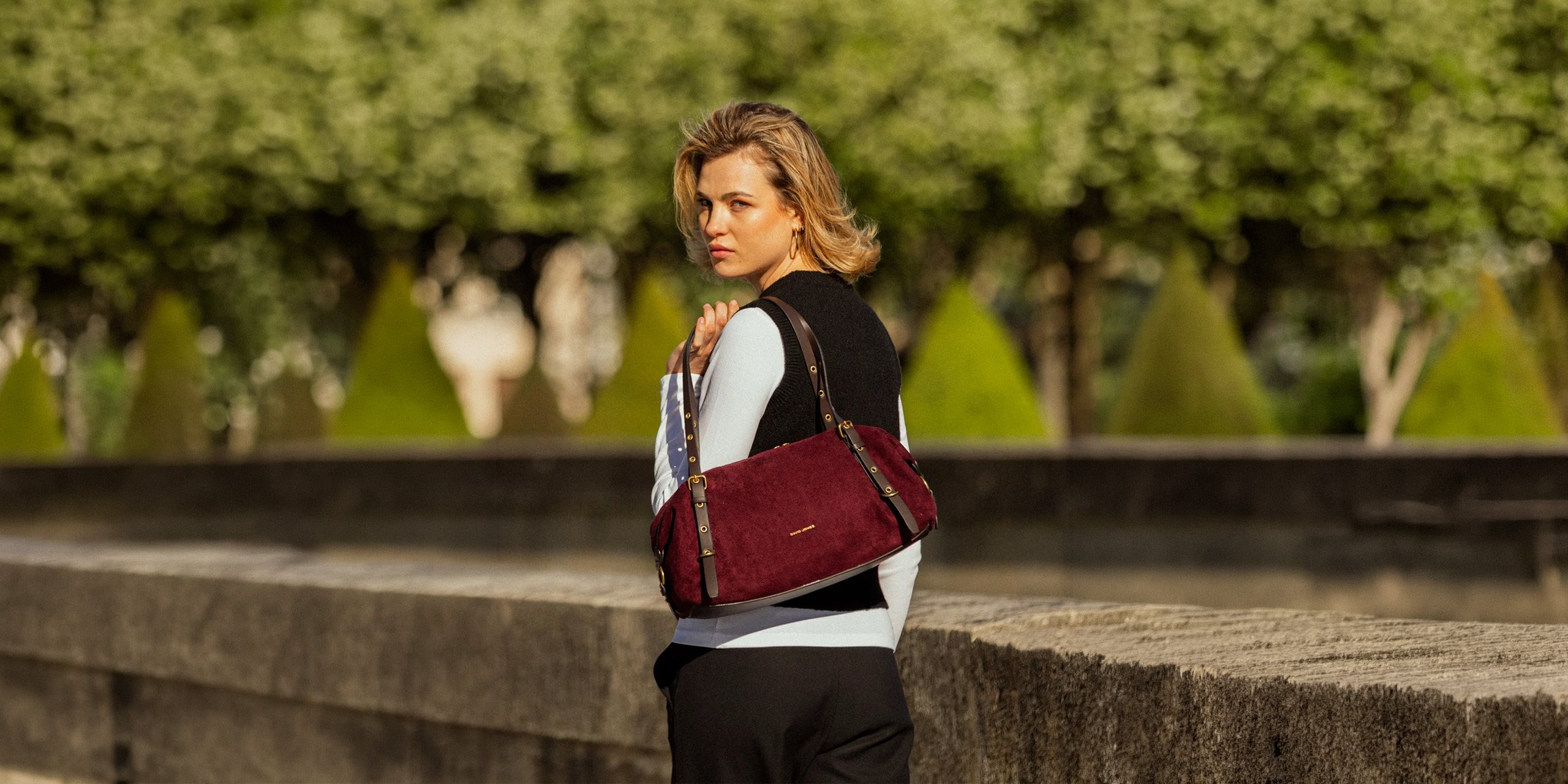 Mujer en un jardín de París con bolso de hombro David Jones color vino